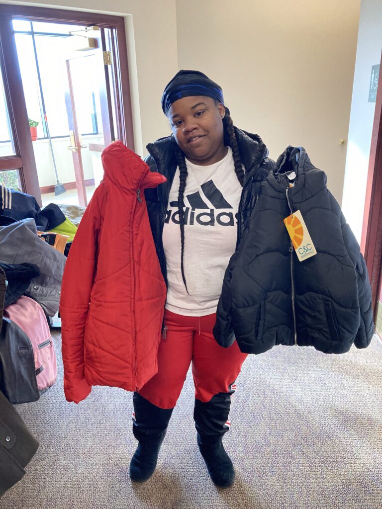 An individual holding up two coats, one red and one black.