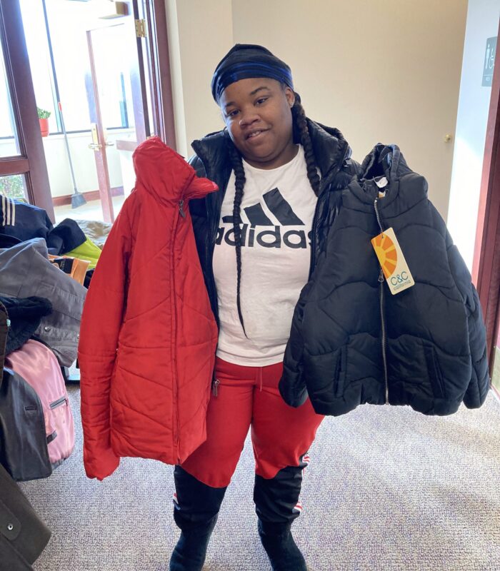 image1services An individual holding up two coats, one red and one black.