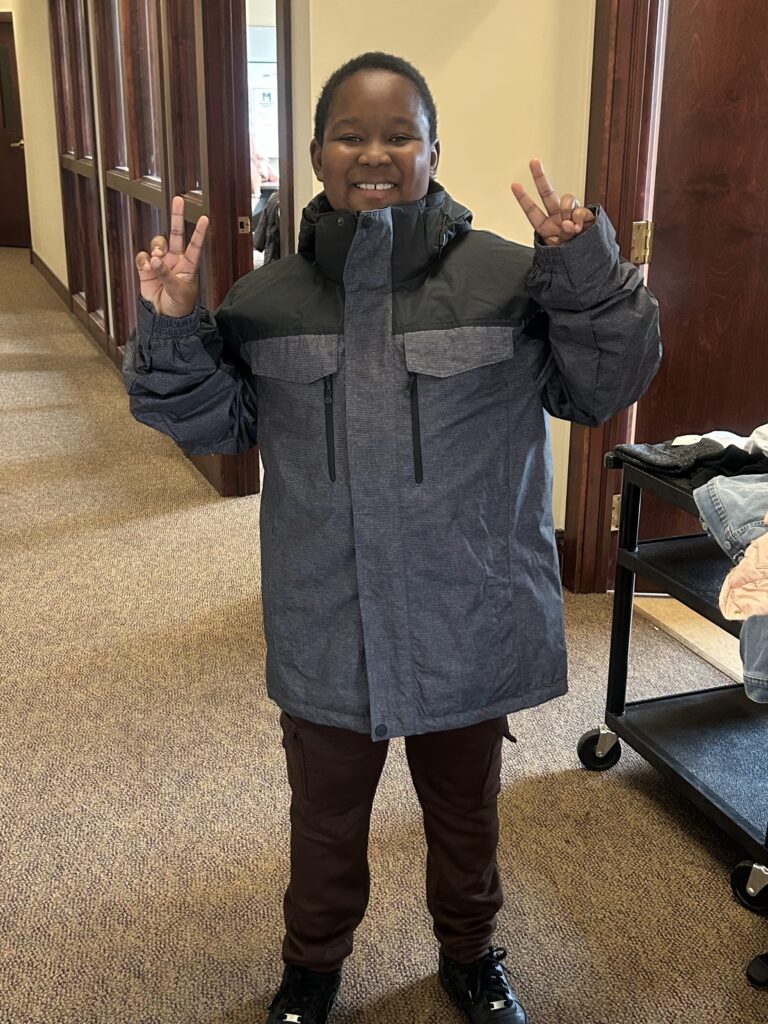 image of child giving peace sign wearing a coat